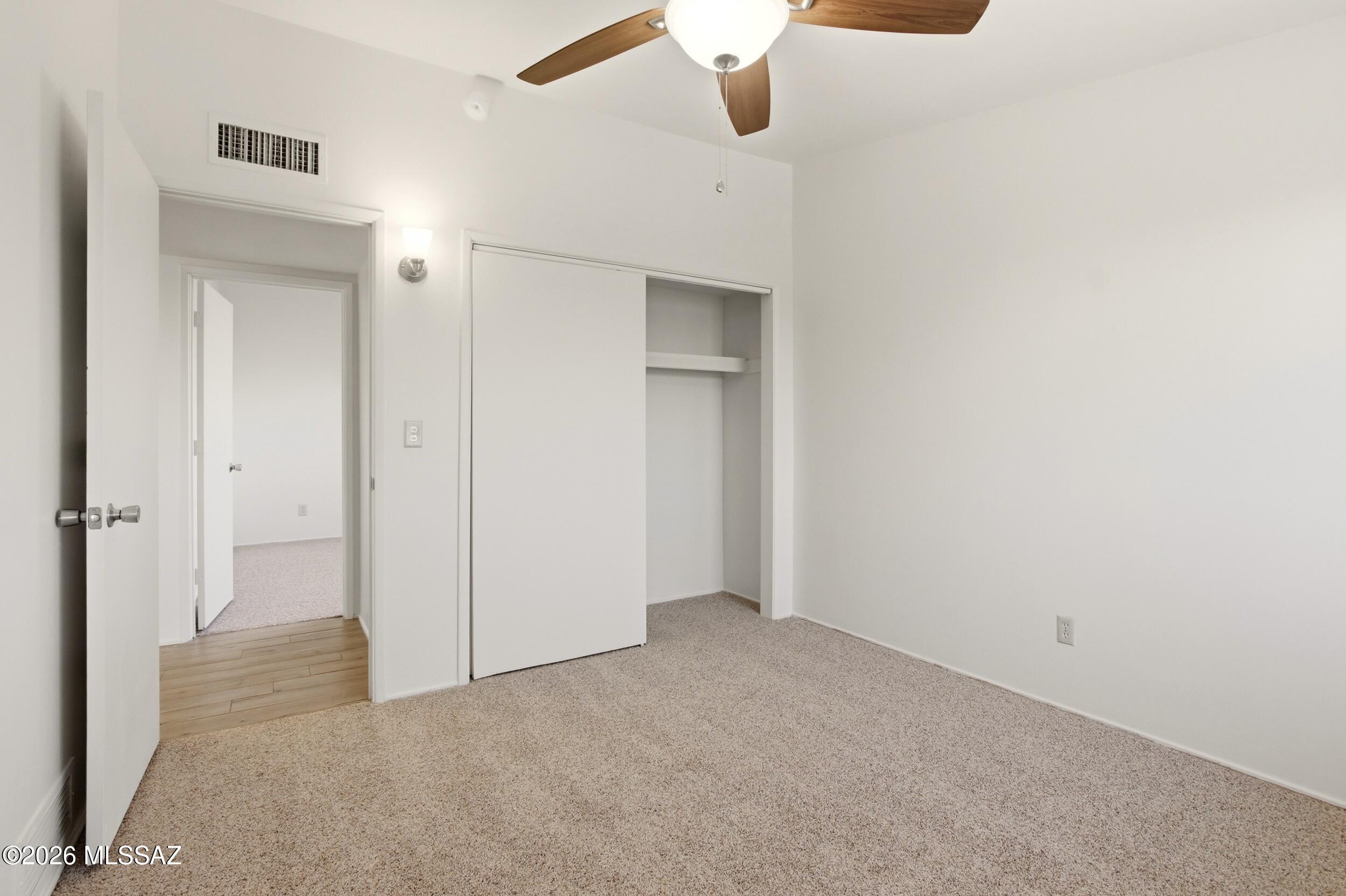 9141 East Indian Canyon Road Tucson, AZ 85749 - Photo 23 of 33 an empty room with a hallway and a chandelier fan