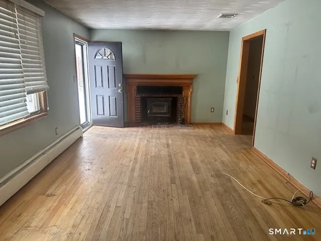 a view of an empty room with a window and fireplace