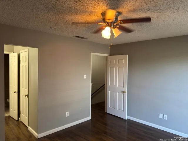 an empty room with wooden floor fan and windows