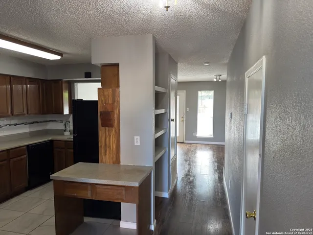 a kitchen with stainless steel appliances granite countertop a refrigerator a sink dishwasher a stove and white countertops with wooden floor