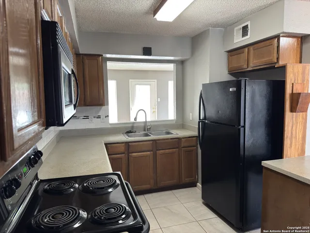 a kitchen with a sink a refrigerator and cabinets