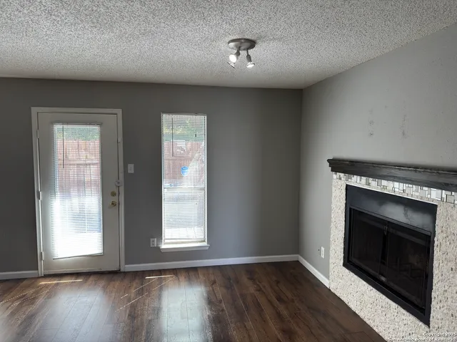 an empty room with wooden floor fireplace and windows