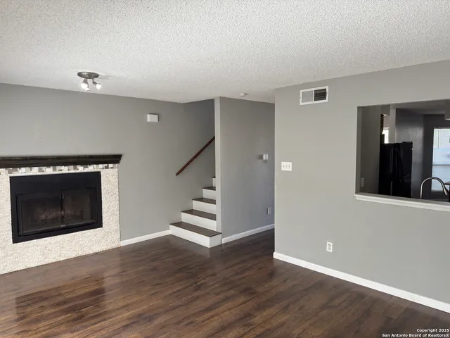 a view of an empty room with wooden floor fireplace and a window