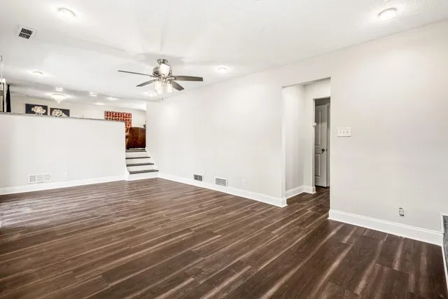 an empty room with wooden floor and ceiling fan