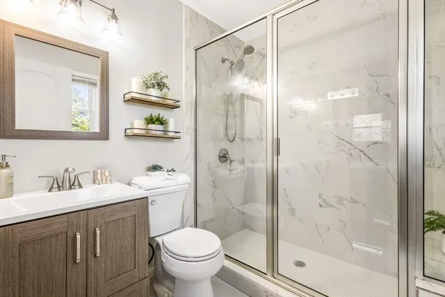 a bathroom with a shower sink vanity mirror and toilet
