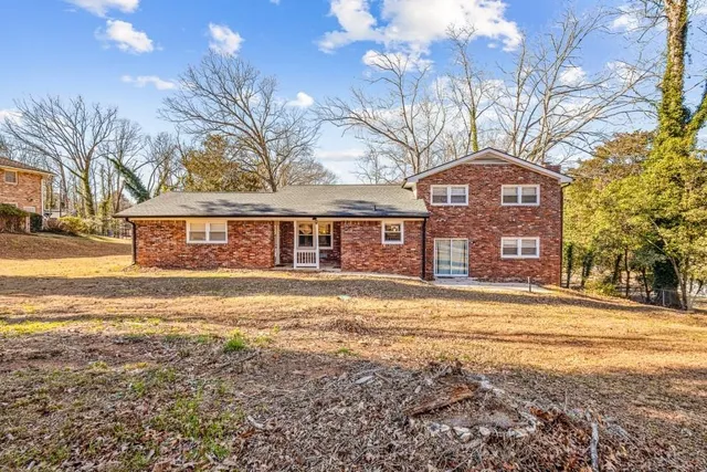a front view of a house with a yard and large trees