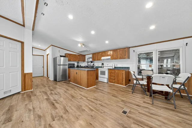 a living room with furniture kitchen view and a wooden floor