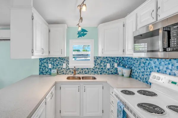 a kitchen with a sink a stove cabinets and wooden floor