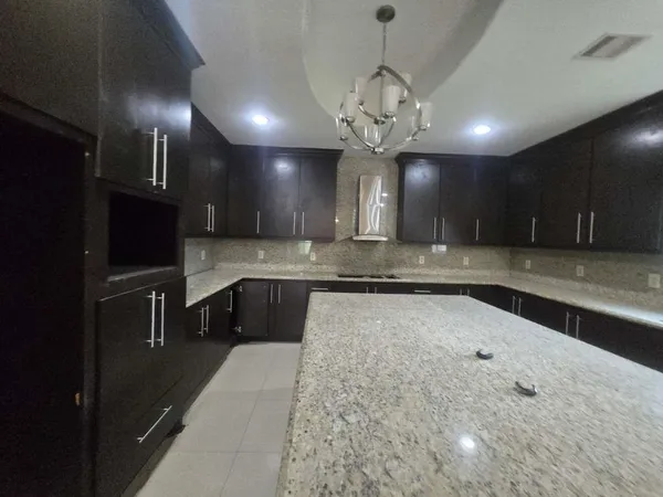 a large kitchen with stainless steel appliances a large counter top a stove and a refrigerator