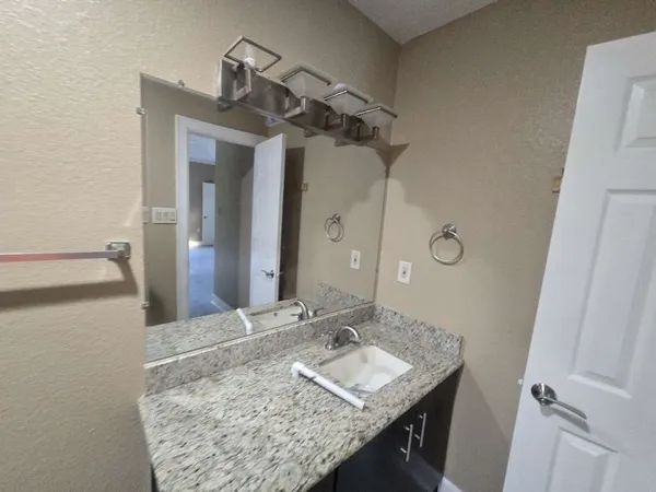a bathroom with a granite countertop sink and a mirror
