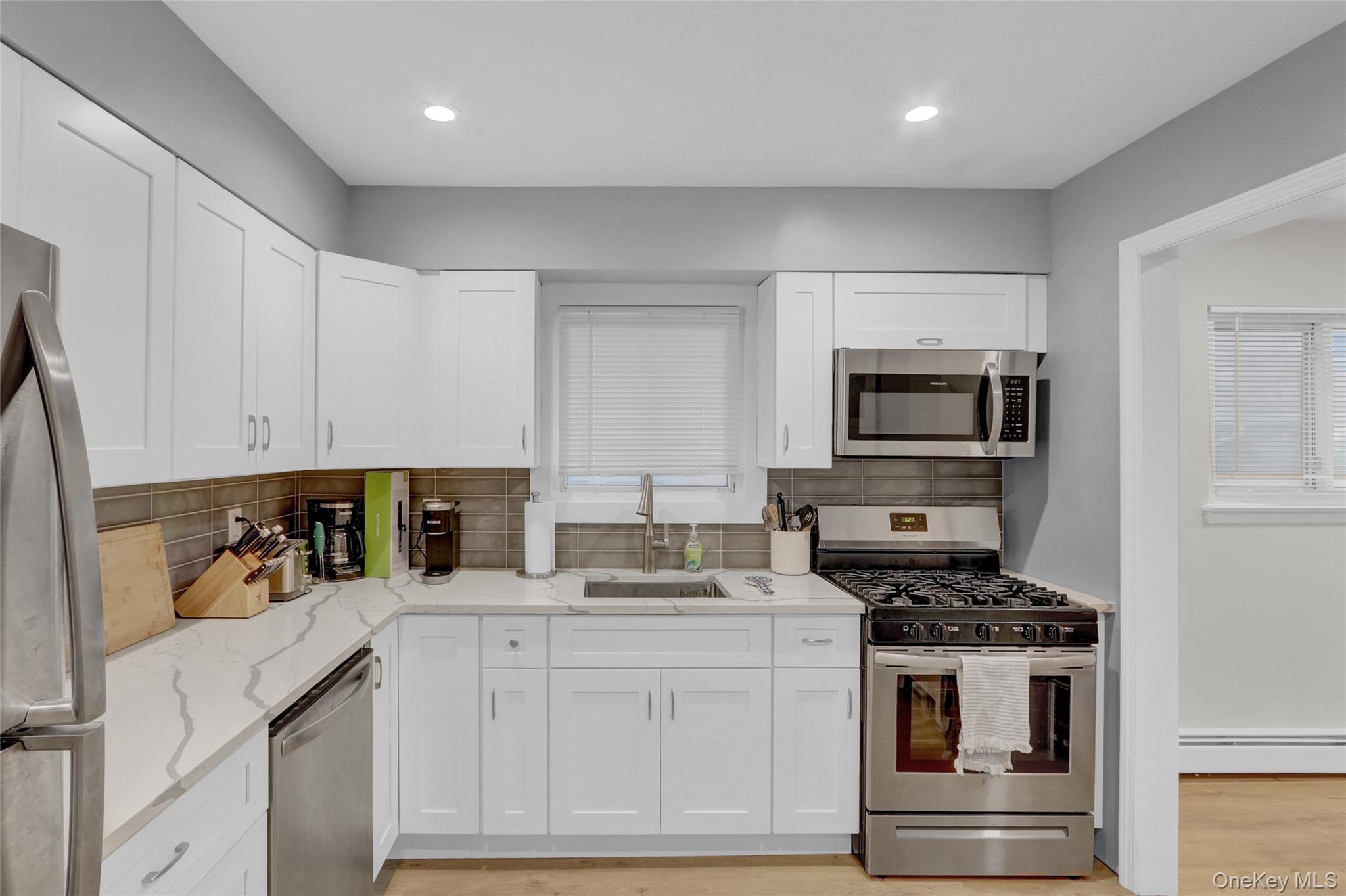 220 East Chester Street Long Beach, NY 11561 - Photo 14 of 26 a kitchen with white cabinets and appliances