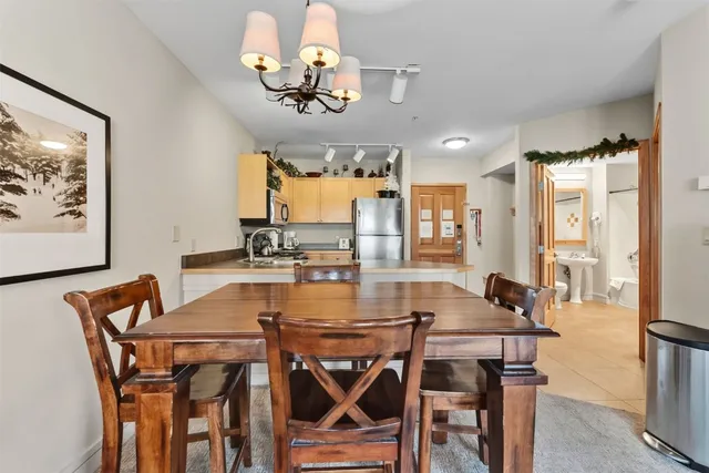 a dining room with wooden floor a chandelier a wooden table and chairs