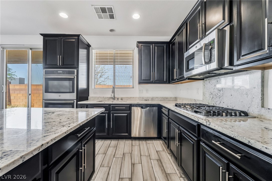 6245 Andover Wood Road Las Vegas, NV 89113 - Photo 12 of 37 Culinary creations come to life in this kitchen, featuring sleek black cabinetry and pristine stone countertops.