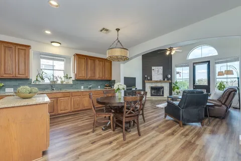 a kitchen with stainless steel appliances granite countertop a stove top oven a dining table and chairs