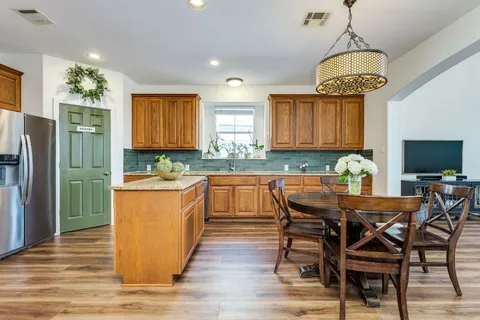 a kitchen with granite countertop wooden floors cabinets a dining table and chairs