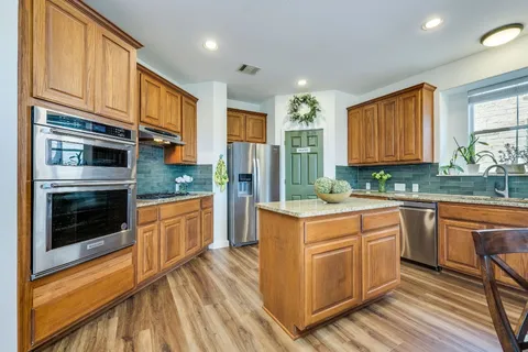 a kitchen with stainless steel appliances granite countertop a stove a sink and a refrigerator