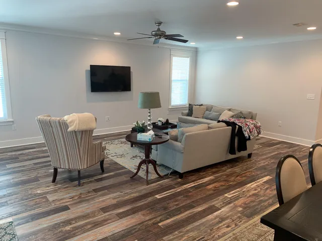 a living room with furniture a flat screen tv and wooden floor