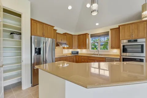 a kitchen with stainless steel appliances granite countertop a refrigerator a stove and a sink with cabinets