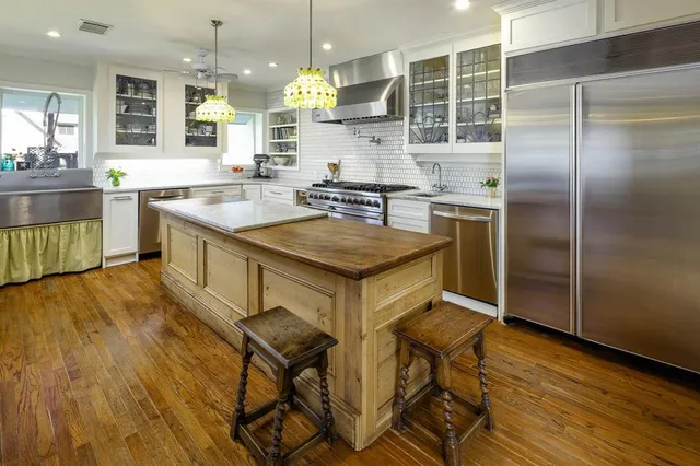 a kitchen with kitchen island a counter top space a sink stainless steel appliances and cabinets