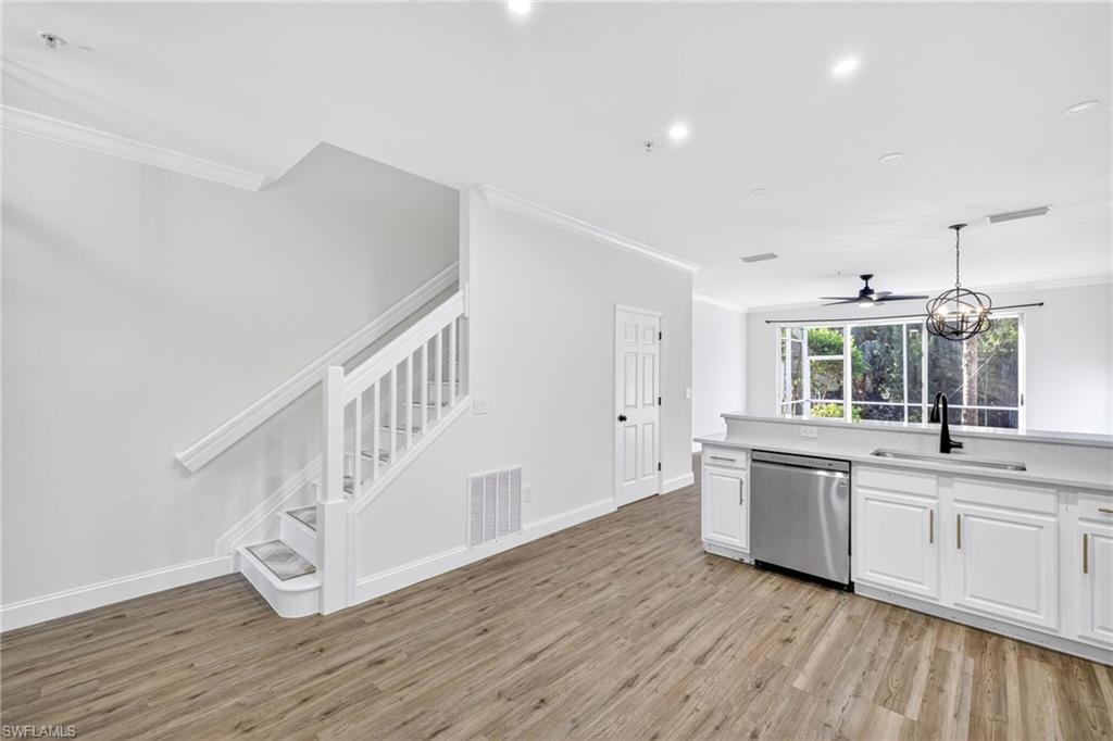 16161 Caldera Lane, Unit 42 Naples, FL 34110 - Photo 2 of 16 a kitchen with wooden floors and white cabinets