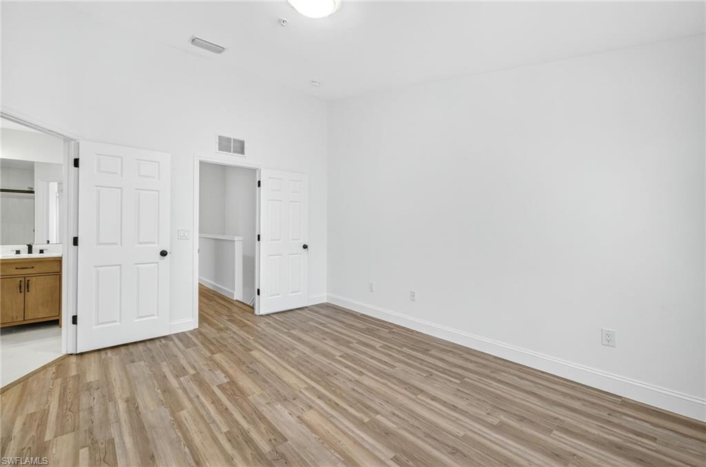 16161 Caldera Lane, Unit 42 Naples, FL 34110 - Photo 7 of 16 a view of an empty room with wooden floor and windows