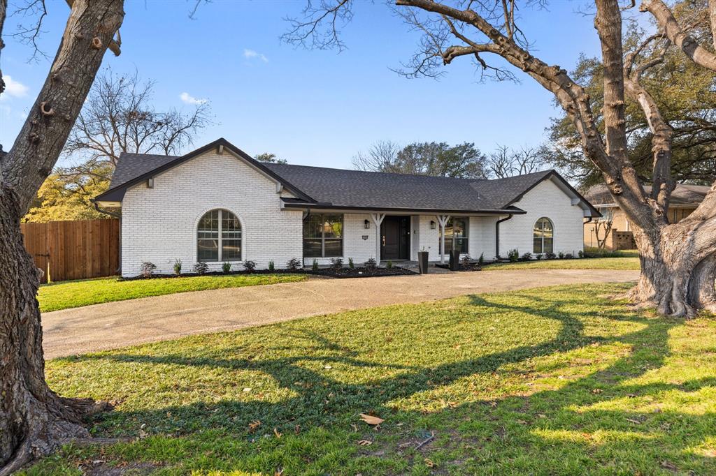 a view of a white house with a yard and large tree