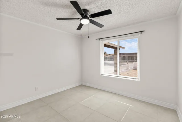 an empty room with ceiling fan and windows