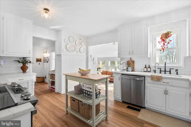 a kitchen with stainless steel appliances granite countertop a refrigerator a stove a sink dishwasher and white cabinets with wooden floor