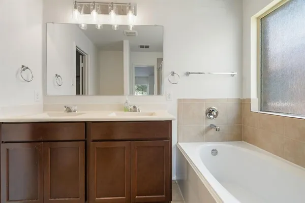 a bathroom with a tub sink and mirror