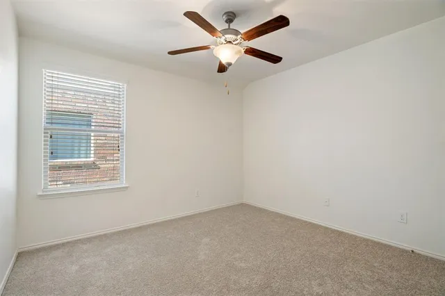 an empty room with a window and a ceiling fan