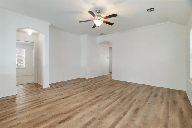 an empty room with wooden floor and ceiling fan