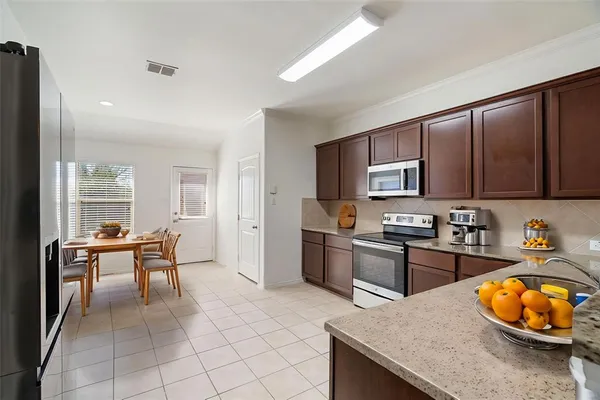 a kitchen with stainless steel appliances granite countertop a stove top oven a sink a dining table and chairs with wooden floor