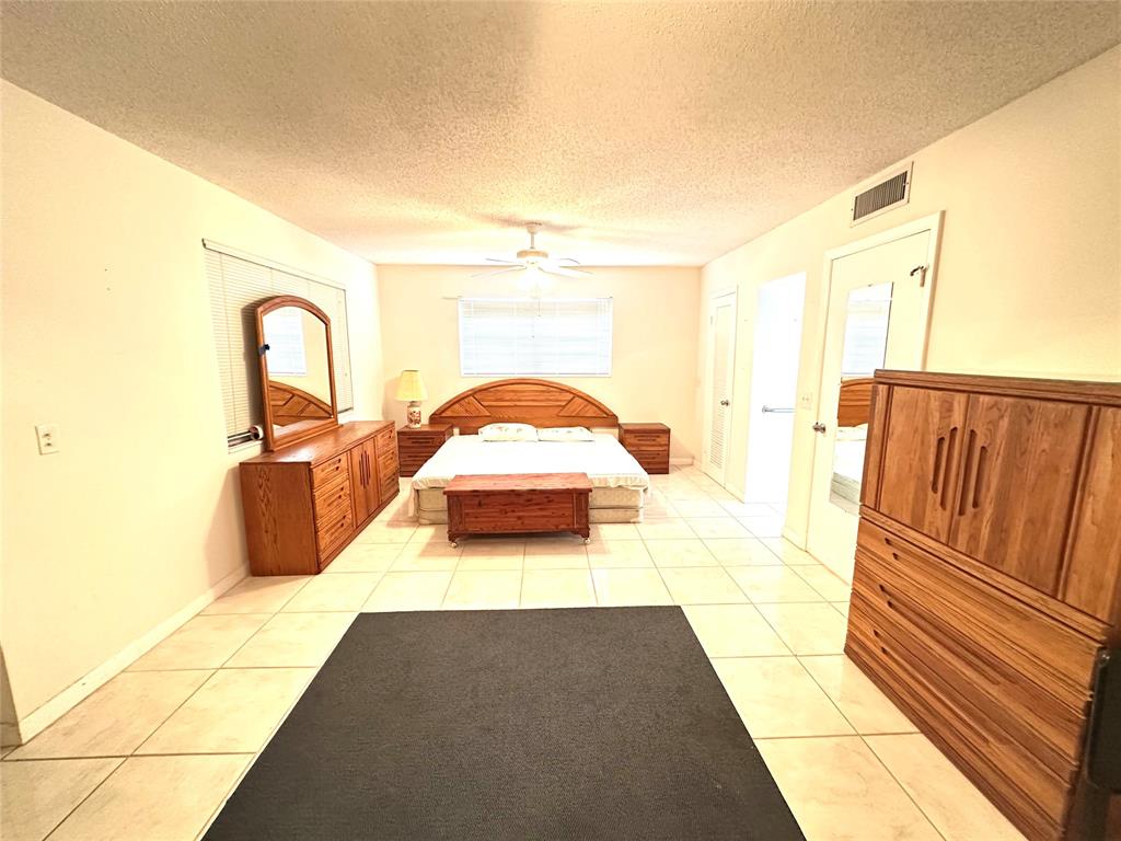 57 Markham C, Unit 57 Deerfield Beach, FL 33442 - Photo 17 of 76 a bedroom with a bed and dresser with mirror