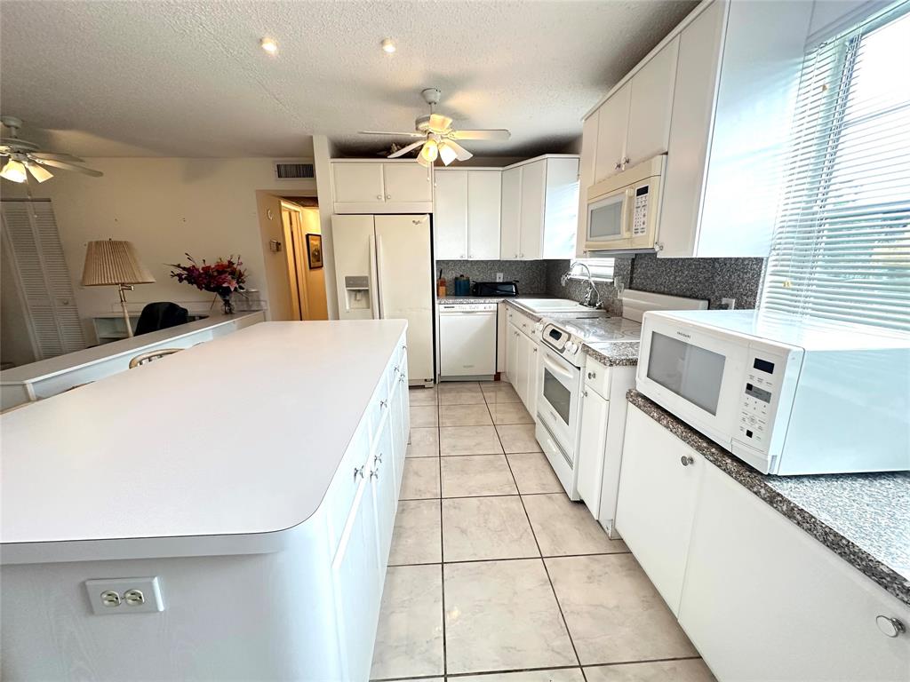 57 Markham C, Unit 57 Deerfield Beach, FL 33442 - Photo 8 of 76 a large white kitchen with a stove a sink dishwasher and a refrigerator