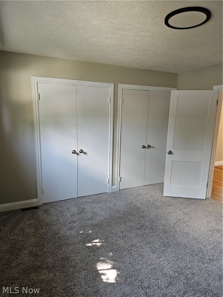1147 Mayfield Ridge Road Cleveland, OH 44124 - Photo 8 of 23 Unfurnished bedroom with multiple closets, carpet floors, and a textured ceiling