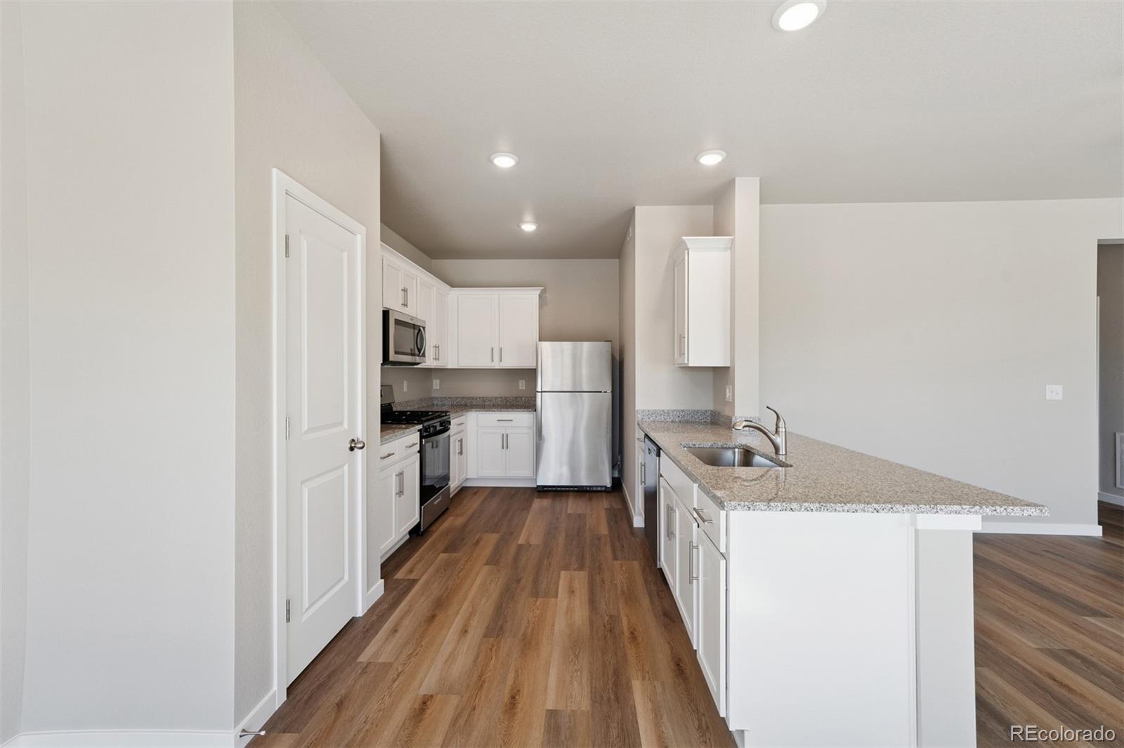 2144 Alyssa Street Fort Lupton, CO 80621 - Photo 2 of 38 a kitchen with kitchen island granite countertop a sink and wooden floor