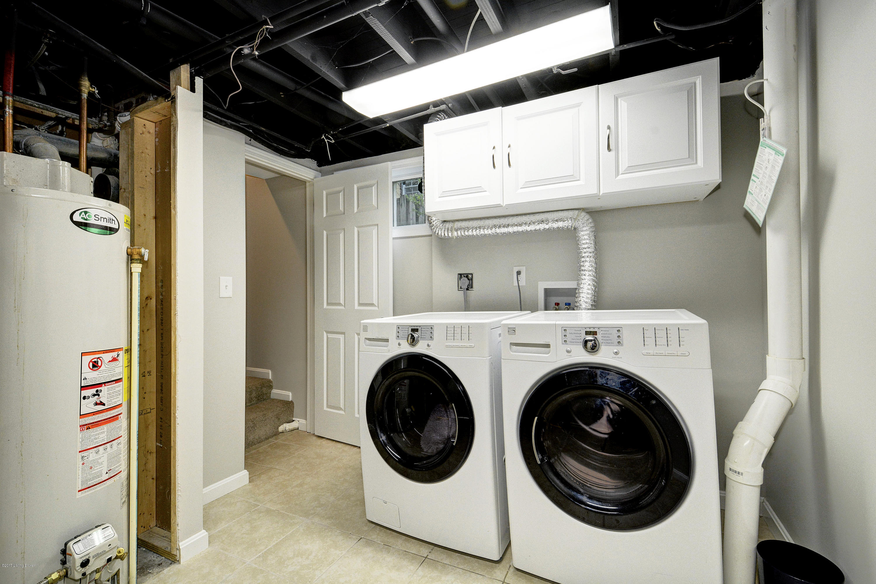 217 Iola Road Louisville, KY 40207 - Photo 34 of 44 The home's dedicated laundry room is complete with a tile floor and white cabinetry.
