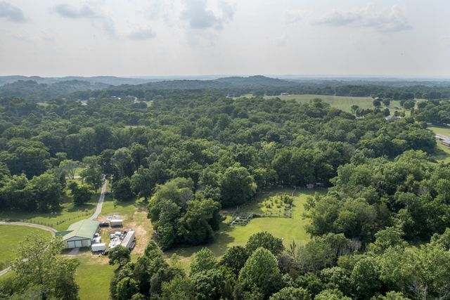an aerial view of residential house with outdoor space and trees all around
