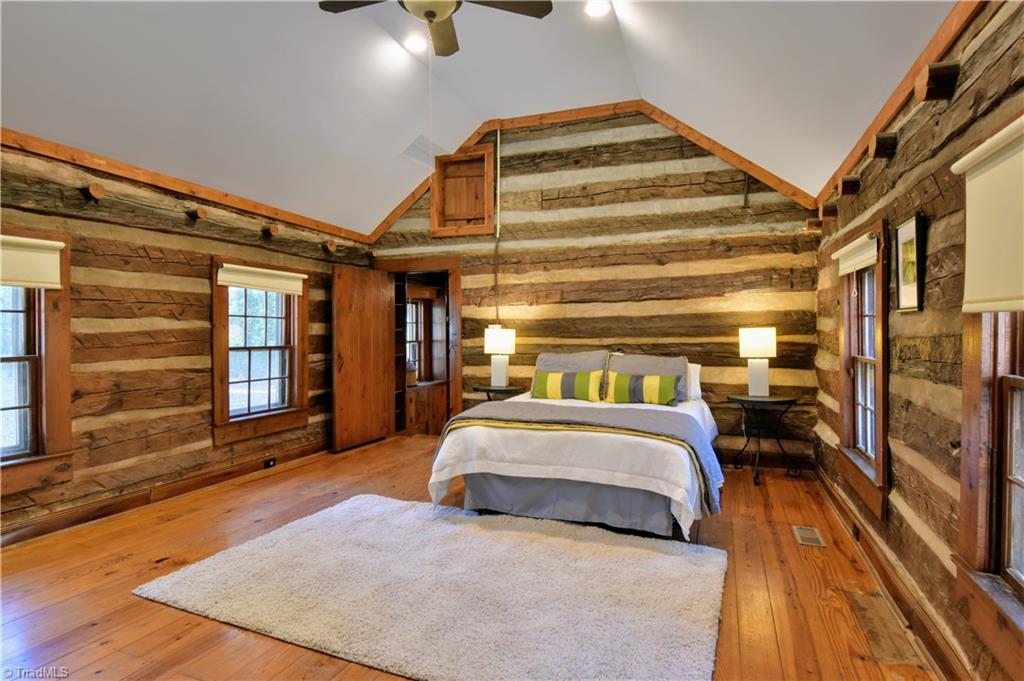 6068 Hedgerow Circle Clemmons, NC 27012 - Photo 13 of 35 Let your worries slip away in this primary master bedroom with smooth white vaulted ceiling, wonderful natural light and log walls blending with other wood textures.