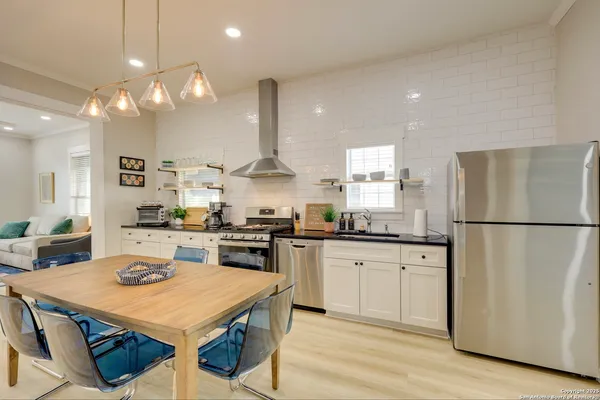 a kitchen with stainless steel appliances kitchen island granite countertop a stove a refrigerator a oven a sink a dining table and chairs