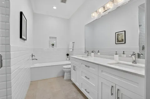 a bathroom with a double vanity sink a toilet a bathtub and shower