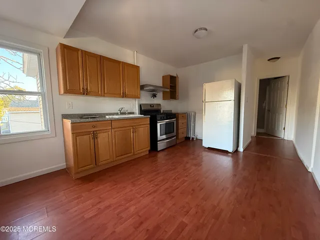 a view of a kitchen with a sink stove cabinets and empty room