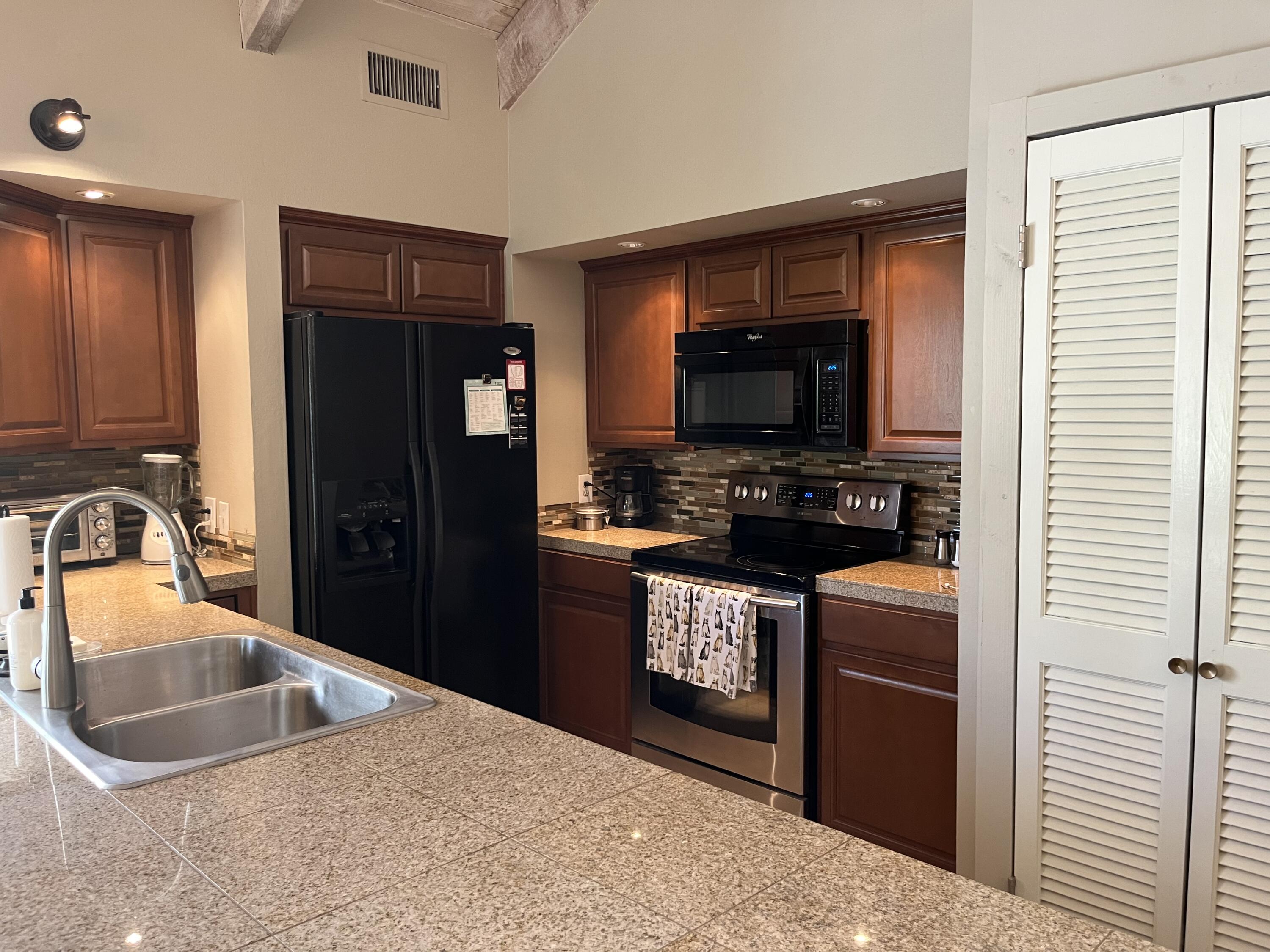 127 South Racquet Club Drive Rancho Mirage, CA 92270 - Photo 11 of 25 a kitchen with granite countertop a refrigerator and a sink