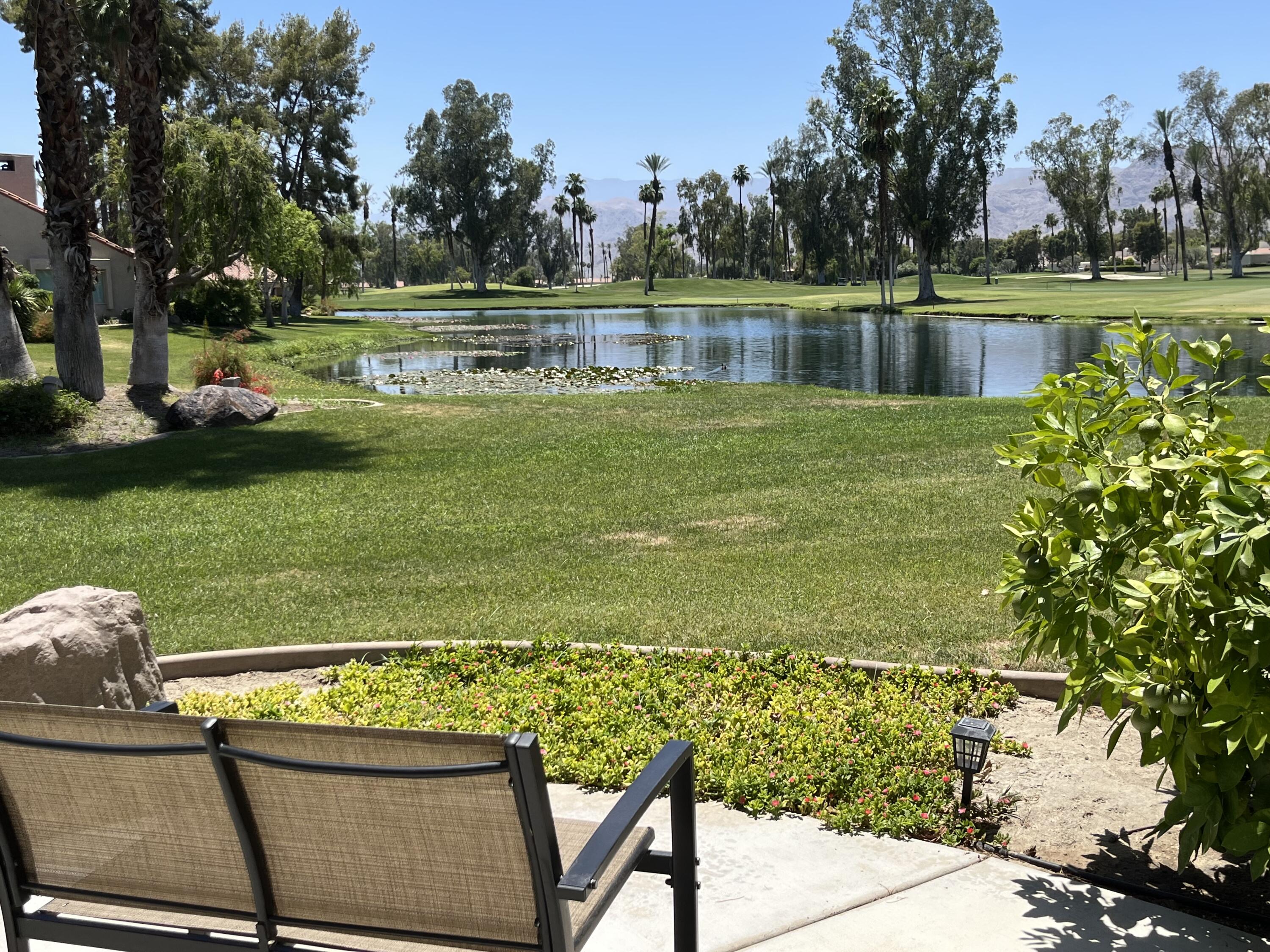 127 South Racquet Club Drive Rancho Mirage, CA 92270 - Photo 4 of 25 a view of a lake with a bench and trees around