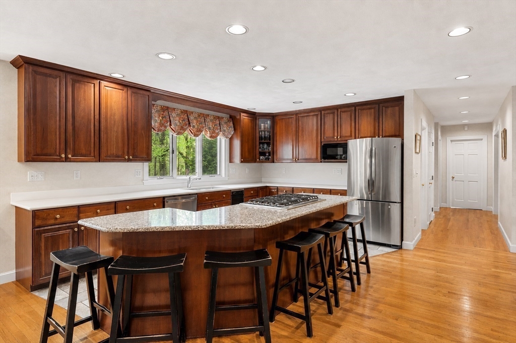 37 Old Planters Road Beverly, MA 01915 - Photo 12 of 42 a kitchen with stainless steel appliances granite countertop a table chairs sink refrigerator and microwave