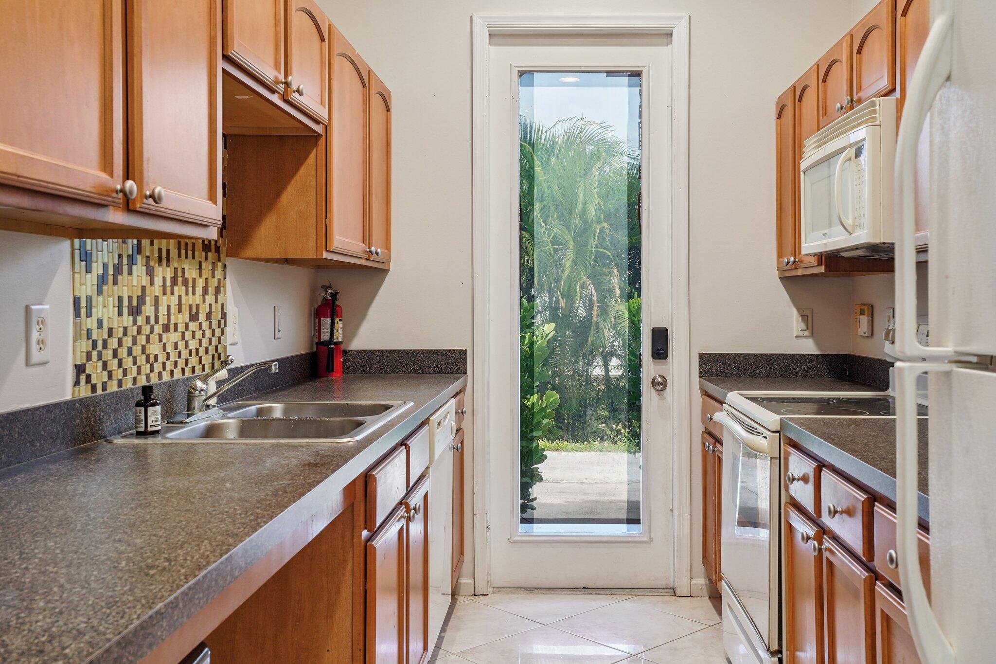 13554 86th Road North West Palm Beach, FL 33412 - Photo 52 of 58 a kitchen with stainless steel appliances granite countertop a sink a stove and a wooden cabinets