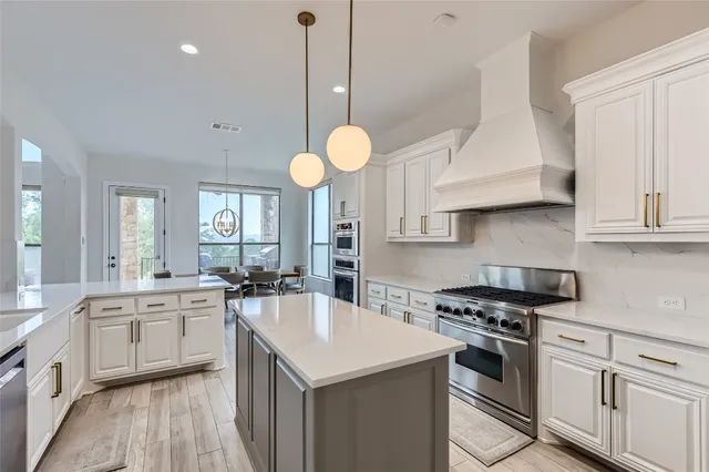 a kitchen with stainless steel appliances a sink a stove and cabinets