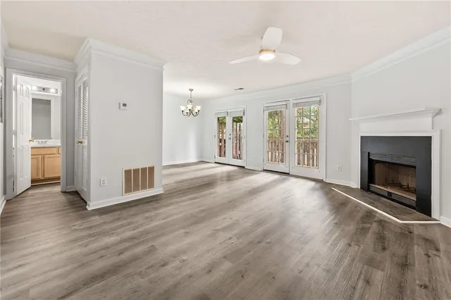 an empty room with wooden floor fireplace and windows