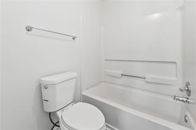 a white toilet sitting next to a bath tub