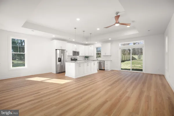 a kitchen with stainless steel appliances granite countertop a refrigerator a sink dishwasher a stove and white countertops with wooden floor